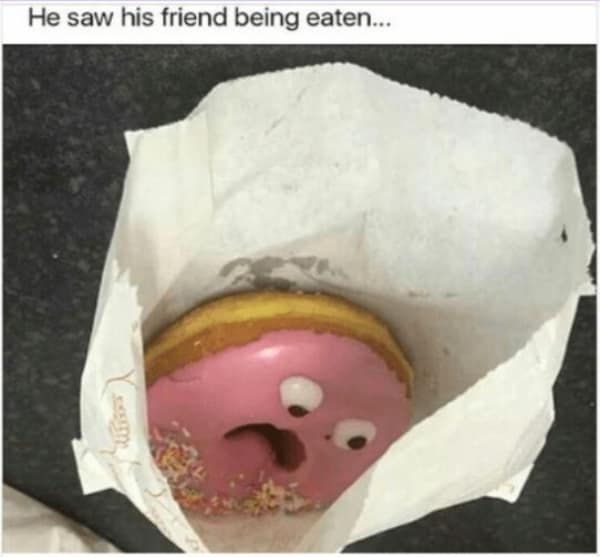 A pink frosted donut with sprinkles inside a white paper bag features candy googly eyes and a bite taken out of it to mimic a screaming mouth in a hilarious food meme.