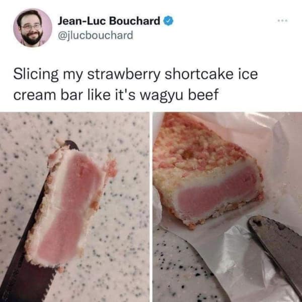 A strawberry shortcake ice cream bar is sliced cleanly down the center with a serrated kitchen knife to display its marbled pink and white cross-section like high-grade wagyu beef in a popular food meme.