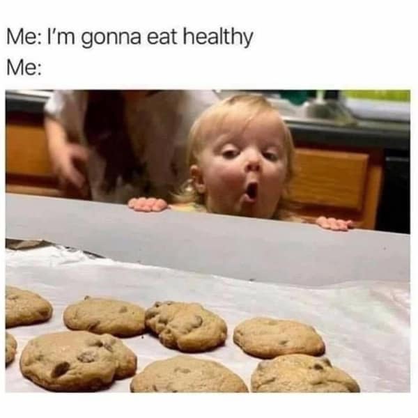 A toddler peeks over a kitchen counter with a look of absolute awe and amazement at a tray of freshly baked chocolate chip cookies in a funny food meme about failing a healthy diet.