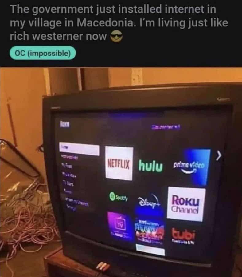 A self-deprecating Reddit post showing a modern Roku smart TV interface displayed on a tiny, ancient CRT television set in a village in Macedonia, with a caption about "living like a rich westerner."