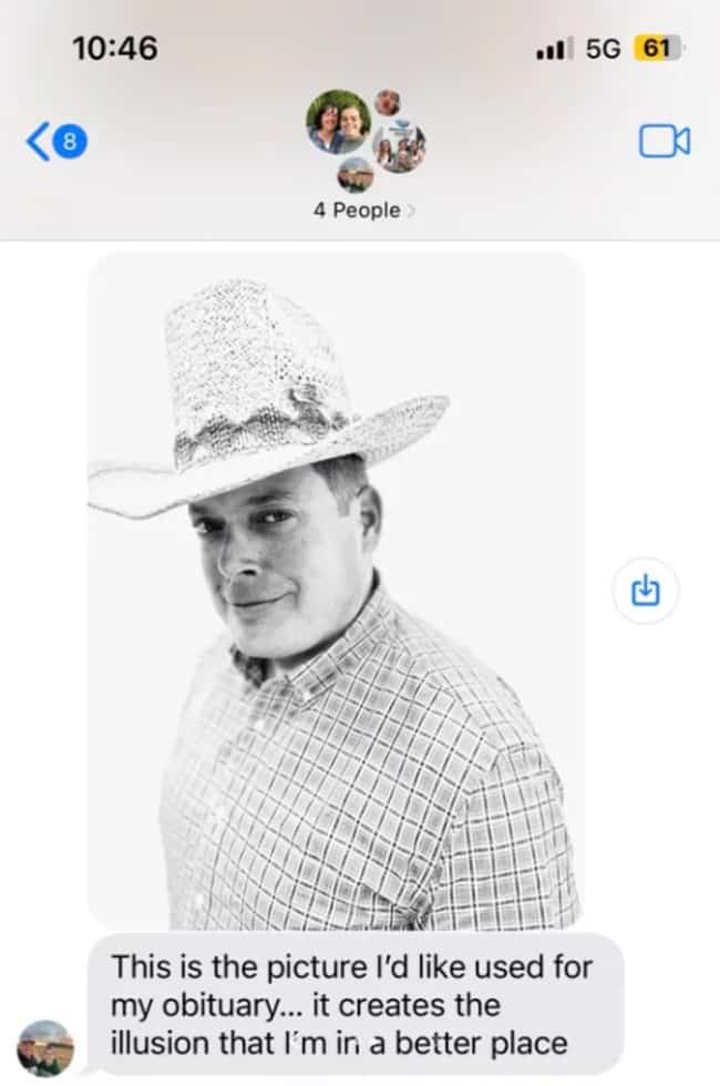 A black and white portrait of a man smiling and wearing a cowboy hat.