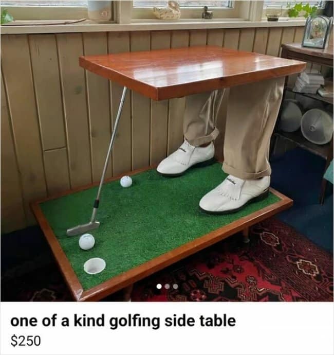 A custom-built novelty side table features a miniature artificial green putting turf base with real golf balls supporting a wooden tabletop resting on realistic mannequin legs wearing khakis and golf shoes in a unique funny Facebook marketplace ad.