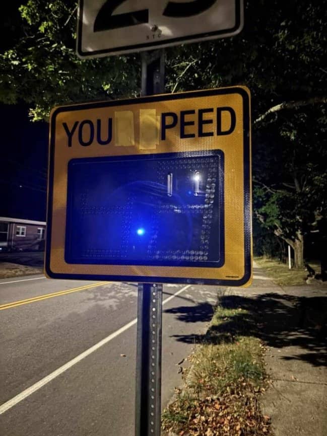 A digital speed radar sign with taped over letters changing the warning message entirely.