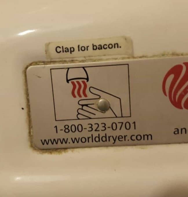 A funny label modification on a bathroom hand dryer jokes about the squiggly lines symbol.