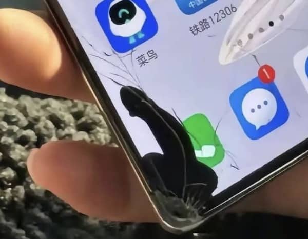 Close up of a cracked smartphone screen with a black ink bleed looking like a silhouette.