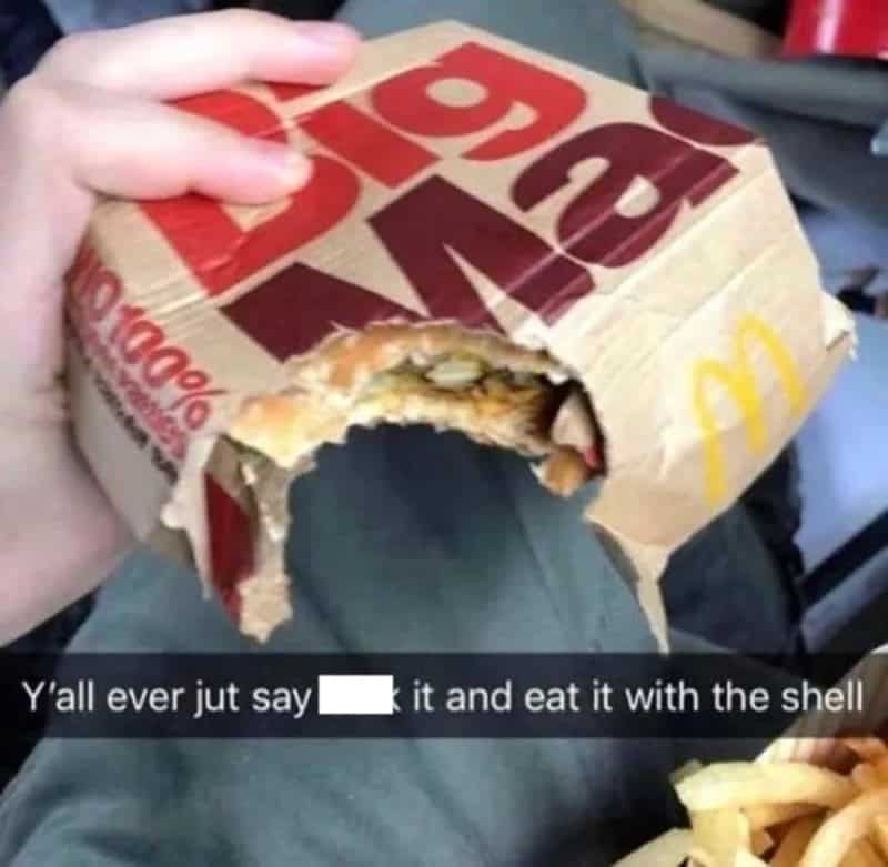 Cursed food image of someone biting directly into a McDonald's Big Mac box like a shell.