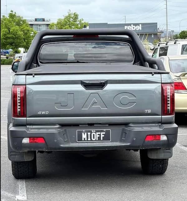 The rear of a grey JAC 4WD truck with a vanity license plate that spells out an inappropriate joke.