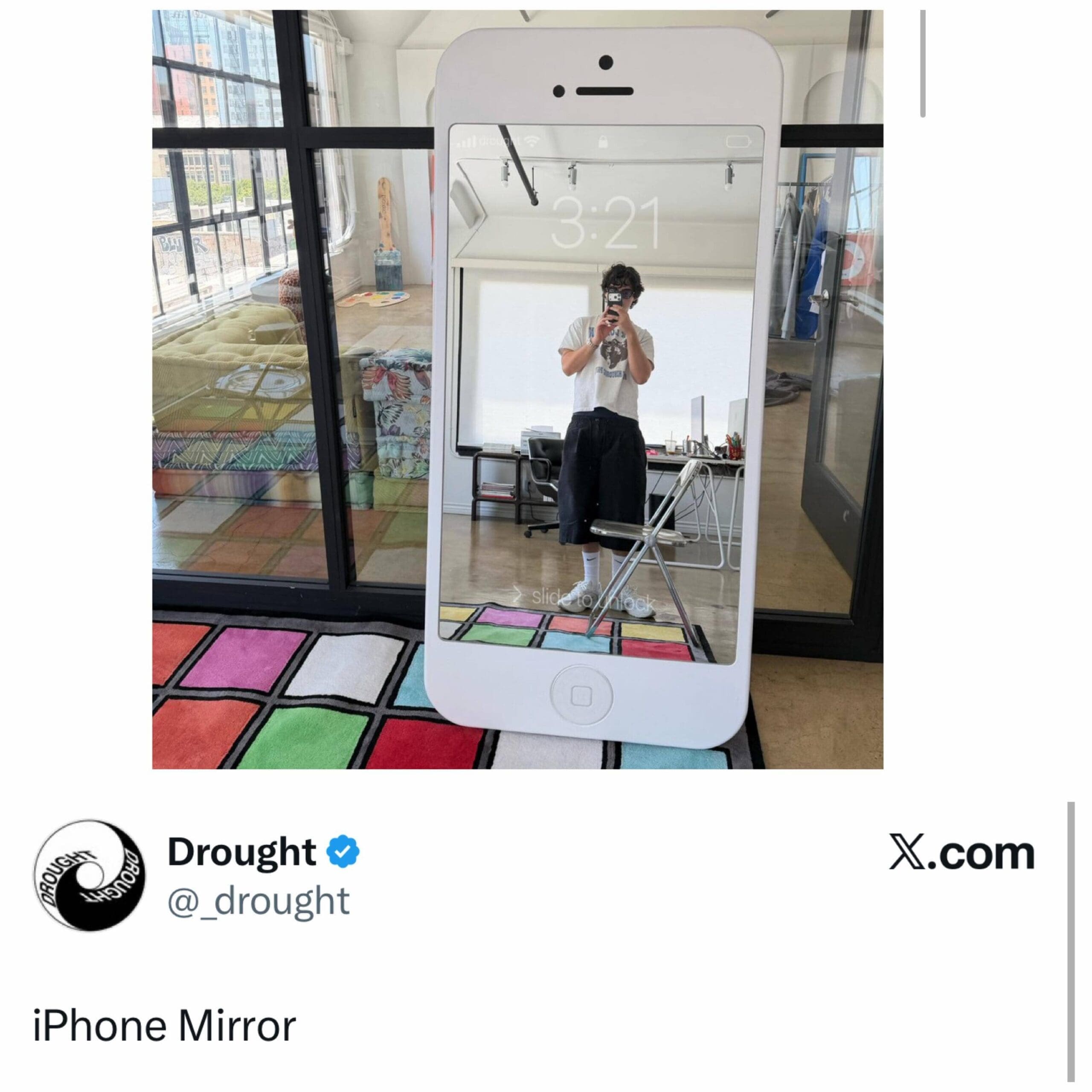 Person taking a mirror selfie using a large novelty mirror shaped like an iPhone.
