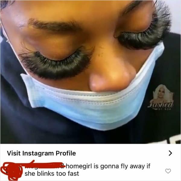 A close-up photo of a woman wearing extremely dense, heavy eyelash extensions that obscure her eyes. The top comment provides a funny roast suggesting she might fly away if she blinks too fast.