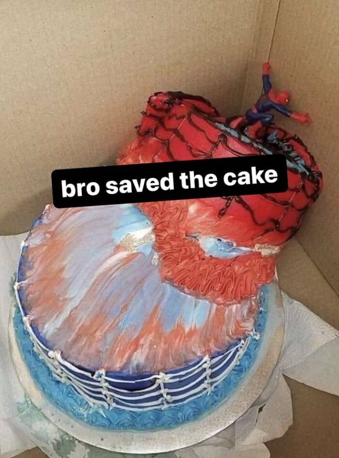 A tilted Spider-Man themed birthday cake that looks like the plastic toy is holding it up.