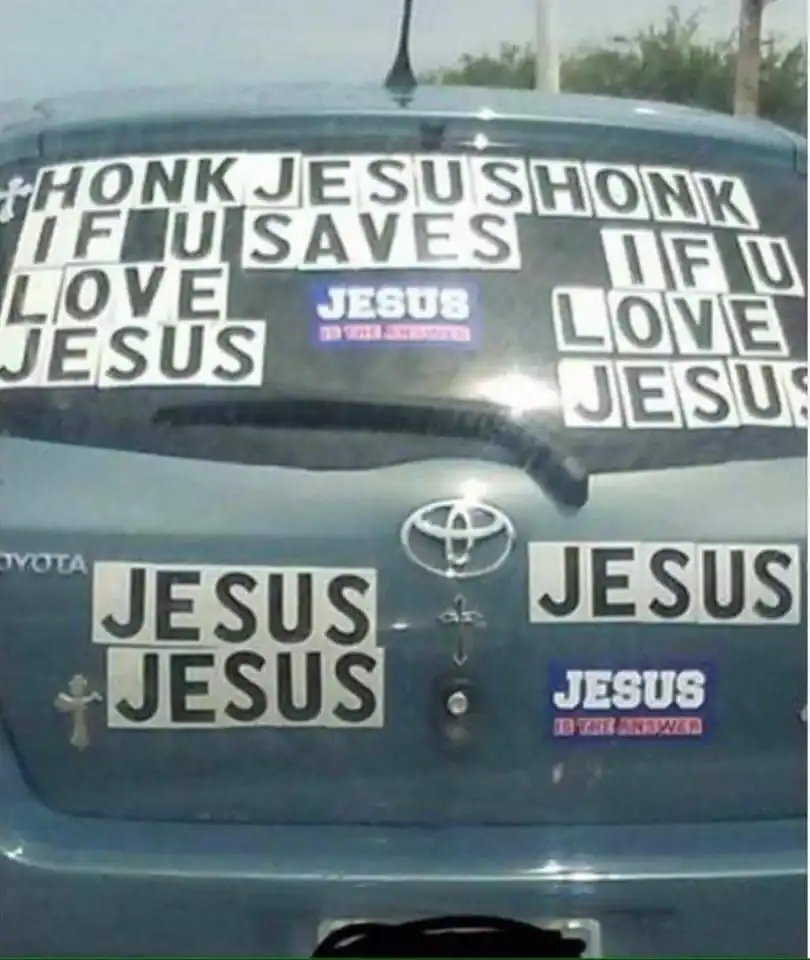 The back of a car covered in a confusing mess of stickers saying honk Jesus.