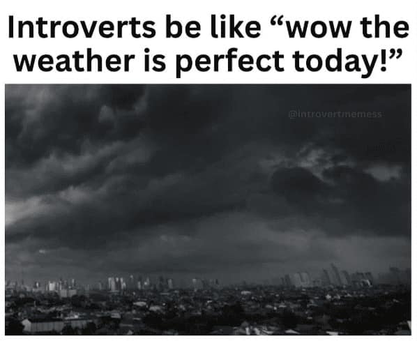 An introvert meme featuring a dark, moody photo of a city skyline under heavy, black storm clouds. The text reads: "Introverts be like 'wow the weather is perfect today!'", highlighting the joy of stay-at-home weather.