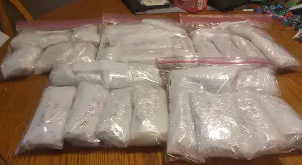 Dozens of small white items wrapped inside clear plastic bags laid on a wooden table.