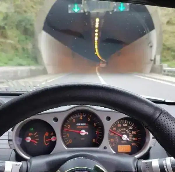 First person driver view entering a highway tunnel shaped like a stylized silhouette.