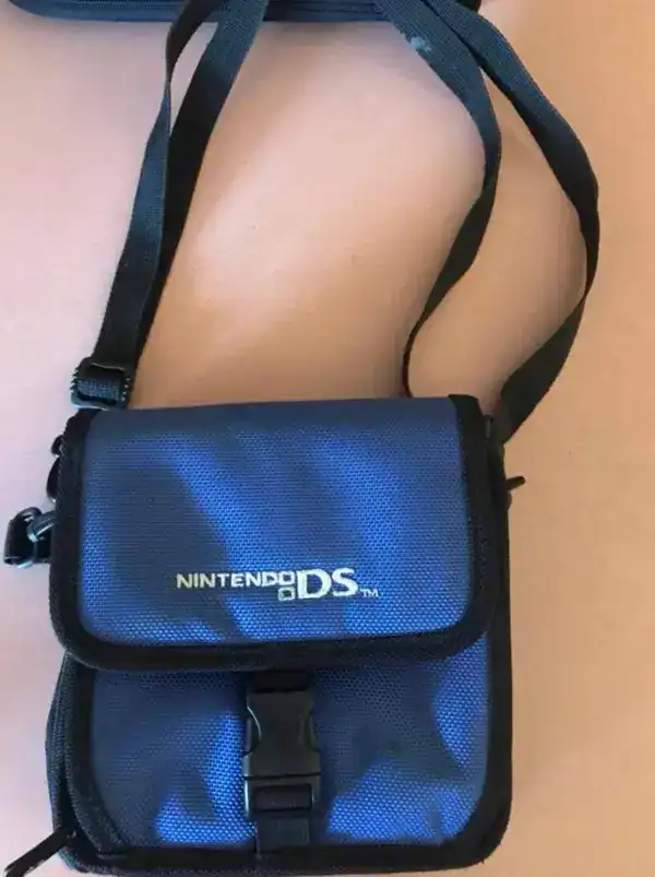 Blue fabric Nintendo DS carrying case resting against a fair skinned person's bare leg.