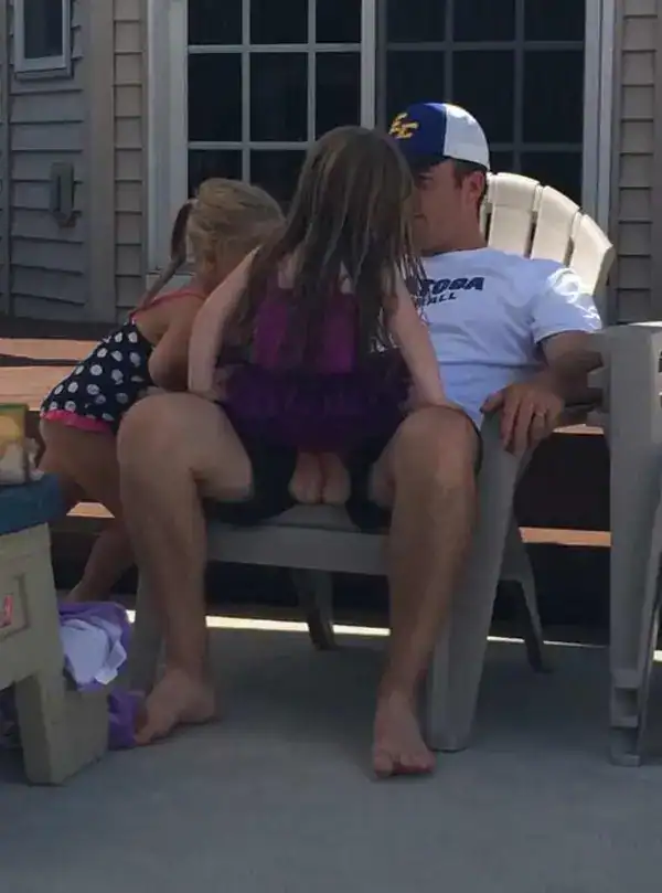 A man sitting on a patio chair with a toddler on his lap creating a confusing perspective.