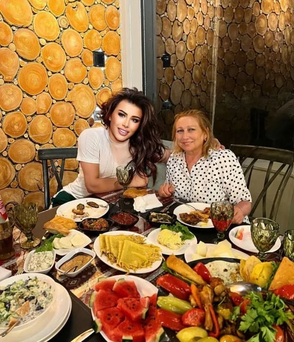 Two women at a dinner table where one has a cartoonishly filtered face.