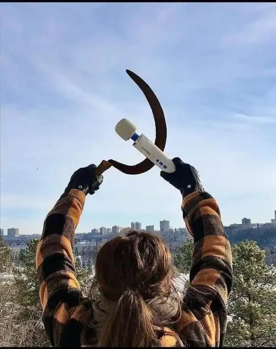 A meanwhile in Russia style image showing a woman silhouetted against a winter skyline, triumphantly holding up a rusty sickle and a white personal massager to mimic the Soviet hammer and sickle symbol.