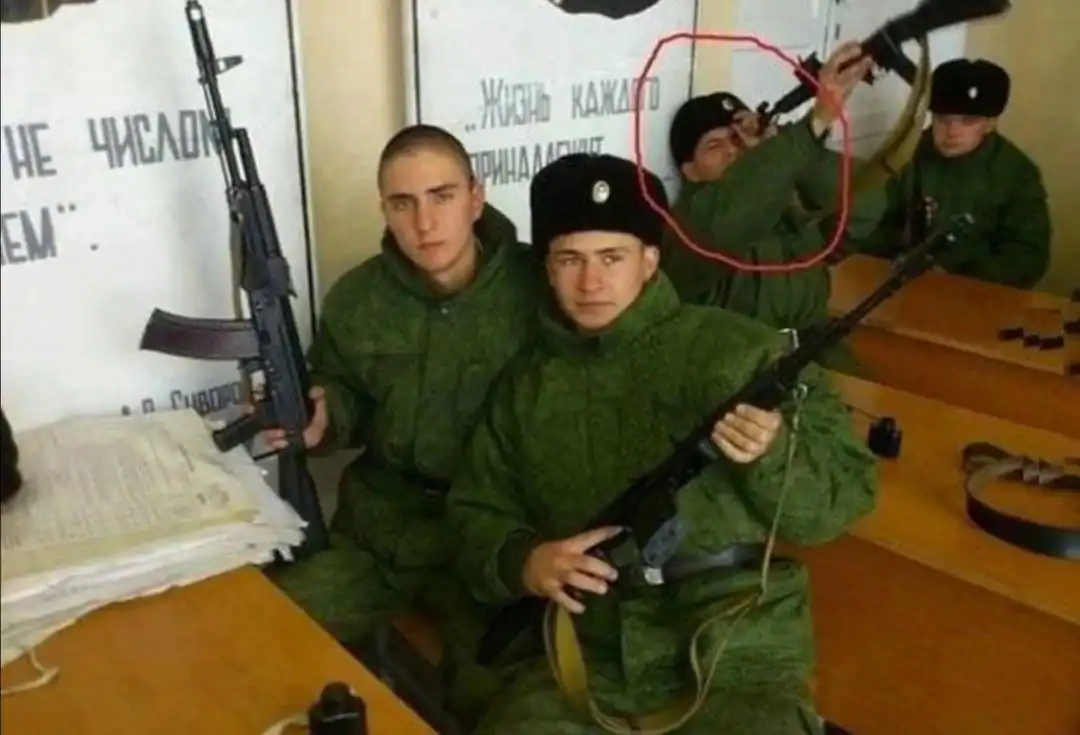A terrifying funny Russia picture from a classroom where a soldier in green fatigues is highlighted with a red circle for pointing the muzzle of his rifle directly into his own eye.