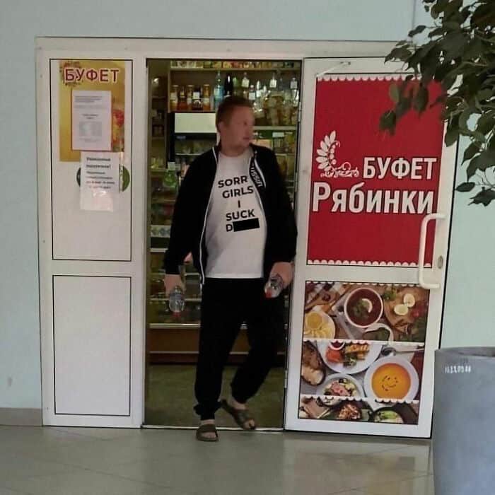 A funny Russia picture showing a man walking out of a "БУФЕТ" (Buffet) wearing a white t-shirt with a highly inappropriate and likely mistranslated English slogan.