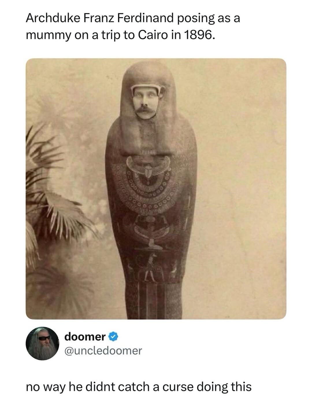 historical photo from 1896 showing Archduke Franz Ferdinand posing as a mummy in Cairo, with a witty reply from @uncledoomer suggesting that this specific moment was the catalyst for his "cursed" assassination and the start of WWI.