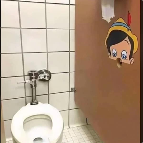 A cursed bathroom stall visual featuring a Pinocchio sticker positioned so that a pre-existing hole in the stall door acts as the character's nose, creating a disturbing voyeuristic effect.