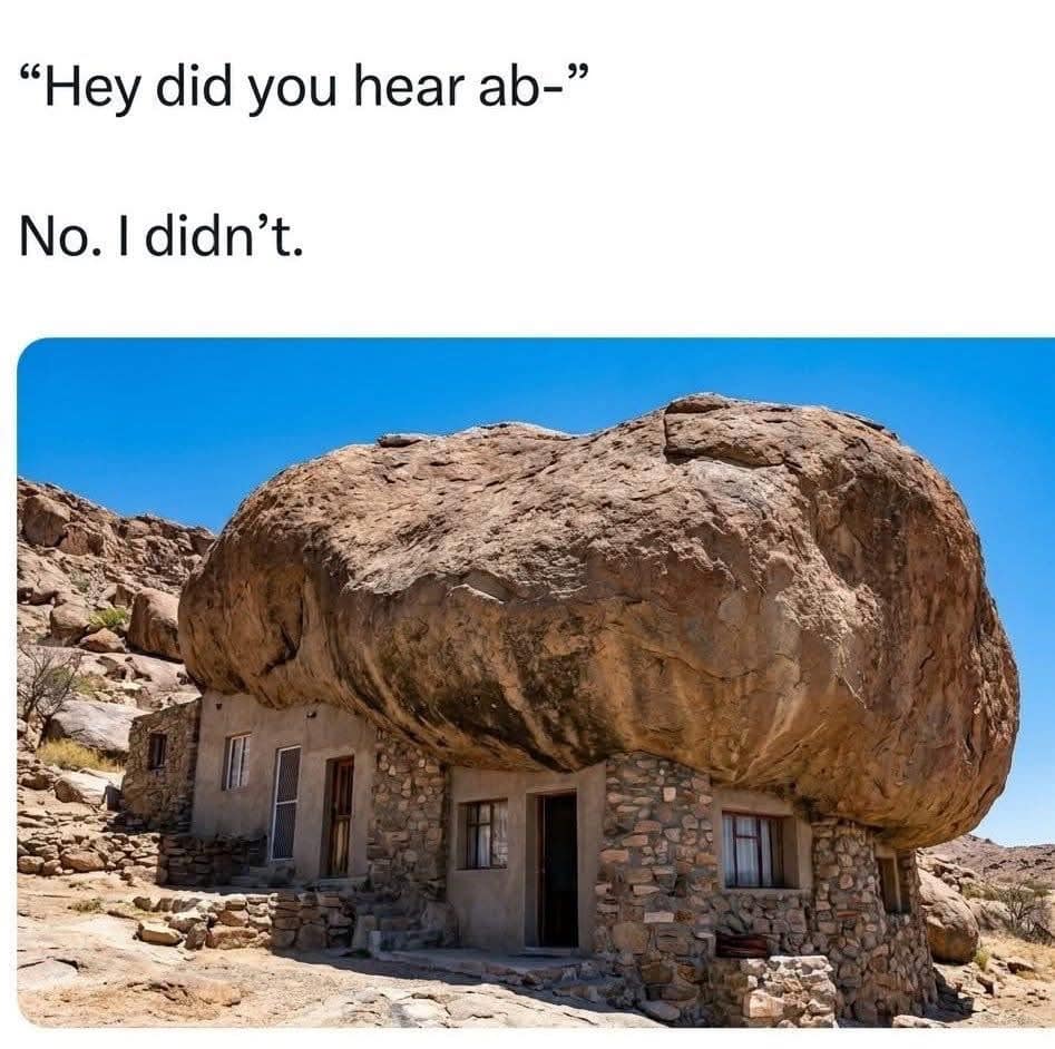 A literalist architecture funny meme showcasing a stone house built directly underneath an imposing, giant round boulder to illustrate living under a rock.