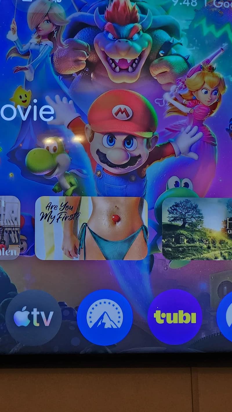 A funny smart TV dashboard alignment captured in a meme dump, where a mature movie tile featuring a woman's bikini-clad waist lines up perfectly beneath an animated portrait of Mario, making him appear to wear a swimsuit and a belly button piercing.