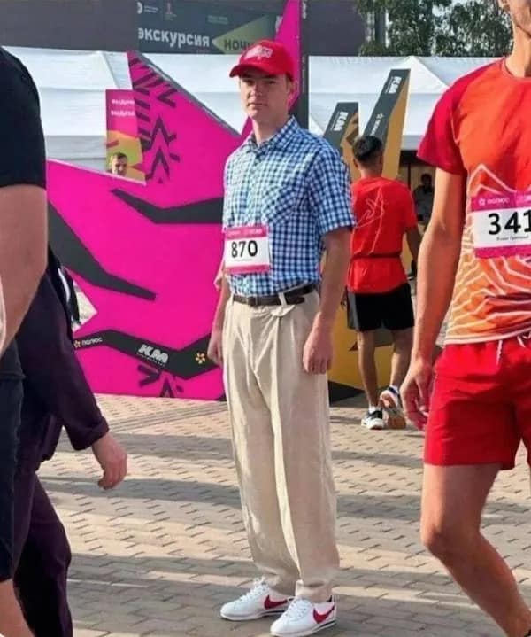 funny meme featuring a man at a public event dressed in the ultimate "dad" uniform: a tucked-in blue plaid shirt, high-waisted khakis, and white Nike sneakers with a red swoosh.