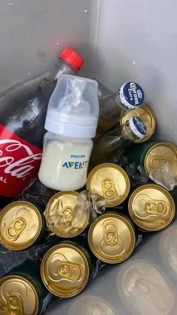 A funny meme of a plastic cooler packed with ice, green beer cans, and Corona bottles, with one single baby bottle filled with milk sitting directly in the center.