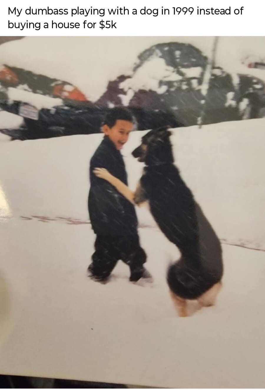A regretful meme dump childhood photo from 1999 showing a small boy playing with a dog in deep snow. The caption mocks his younger self for "playing with a dog in 1999 instead of buying a house for $5k."
