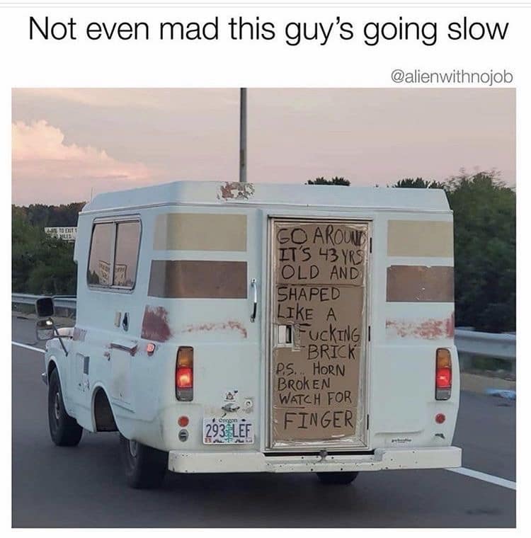 A viral highway photograph featured in a meme dump captures a 43-year-old boxy vintage camper van with a large handwritten cardboard warning sign on the back door explaining that it is shaped like a brick.