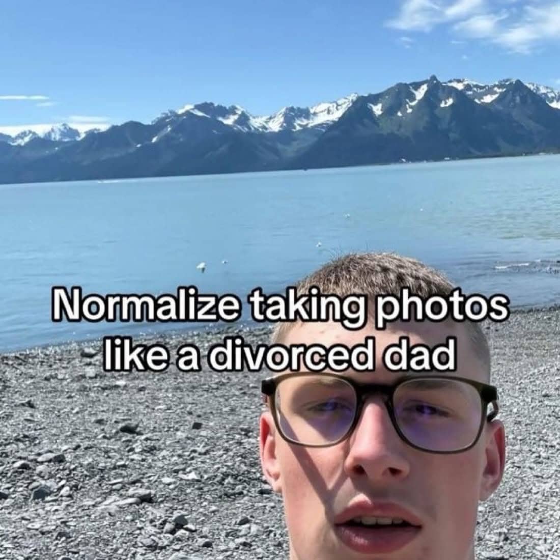 Young man taking a low-angle selfie outdoors captioned with normalize taking photos like a divorced dad.