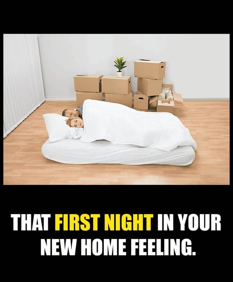 A couple sleeping on a mattress on the floor of an empty house with boxes.