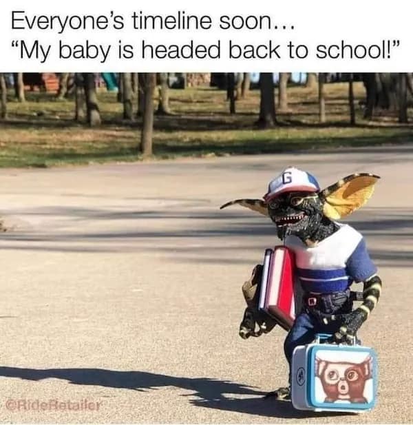 A funny pop-culture macro displays a realistic replica model of a scowling Stripe Gremlin carrying schoolbooks and a Gizmo lunchbox across an asphalt playground under text about back-to-school social media timelines.
