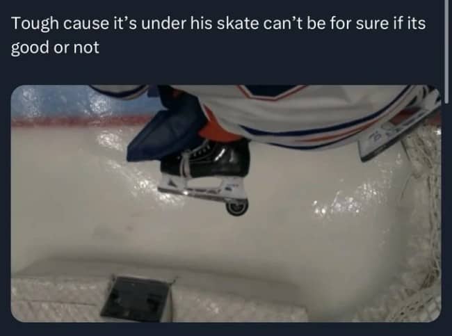Top-down replay view of a hockey puck hidden completely underneath a goalie's skate blade.
