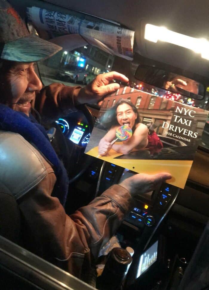 An older NYC taxi driver proudly displays a calendar featuring himself posing with a lollipop.