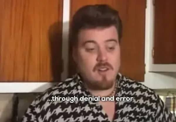 icky with a mustache and goatee in a brown plaid shirt inside a kitchen.