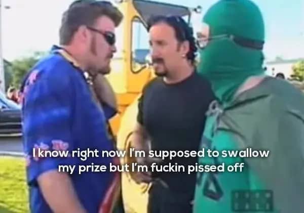 ulian wearing sunglasses in a blue shirt talking to a man in a green ski mask.