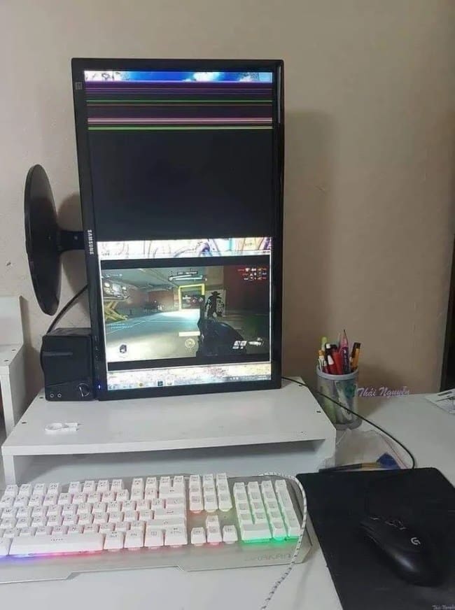 A vertical computer monitor with a shattered top half, displaying a game only on the functional bottom section.