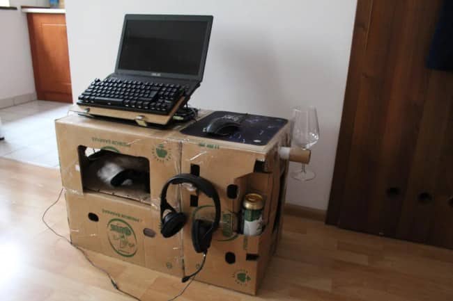 A custom-built computer desk made entirely out of stacked cardboard boxes with a laptop on top.
