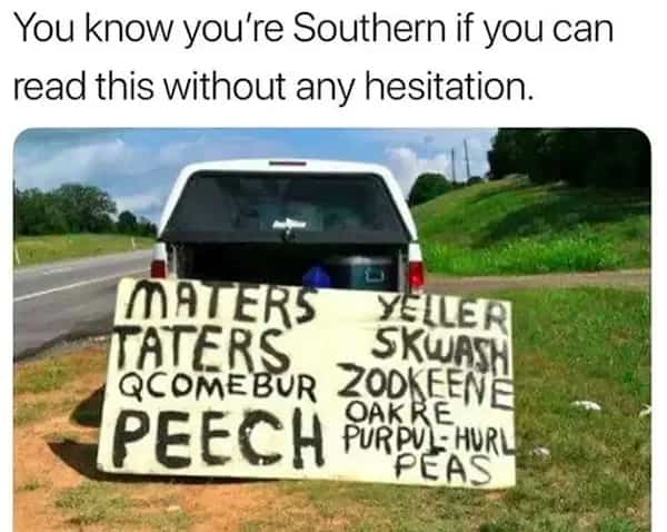Hand-painted wooden sign in a truck bed listing misspelled produce like "Maters" and "Peech."