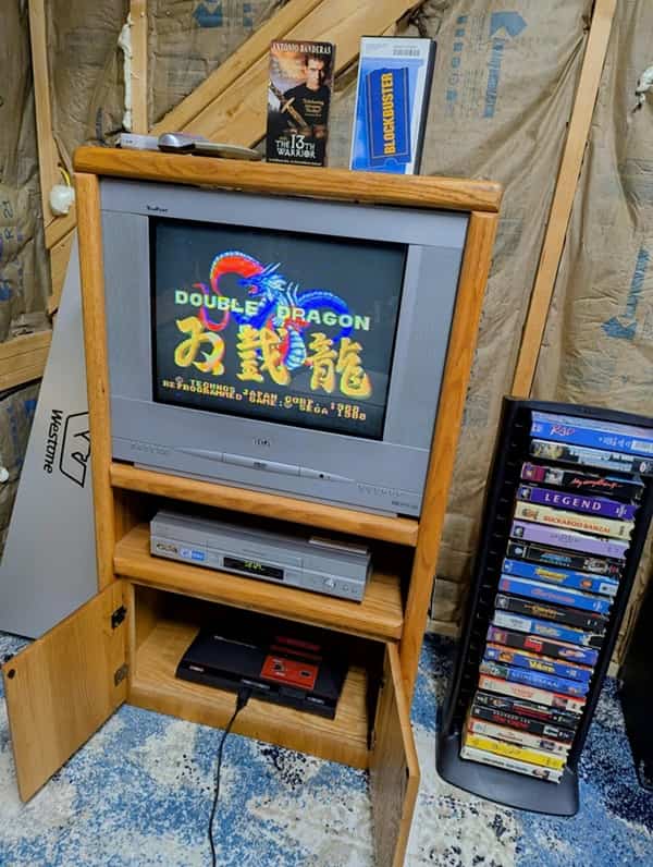 A classic CRT television playing Double Dragon sliding cleanly into a vintage wooden entertainment center.