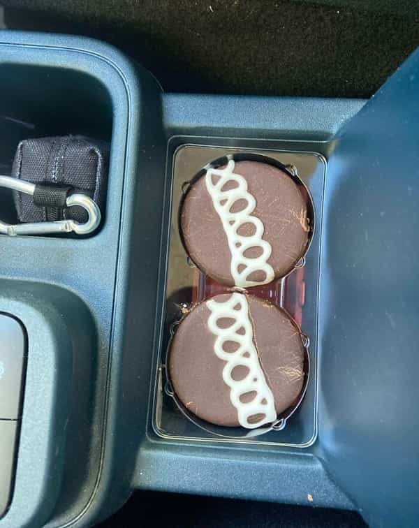 Two chocolate Hostess cupcakes wedged flawlessly into a rectangular center console compartment.