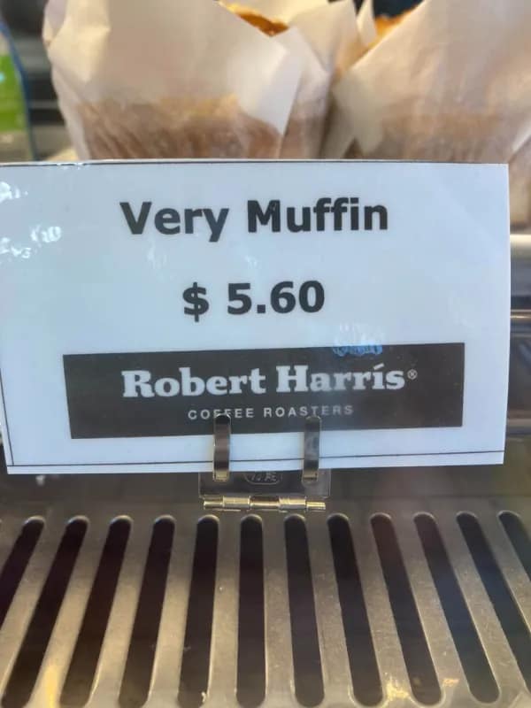 A retail counter display sign at a café features a funny grammatical english fail labeling a standard pastry choice as simply a "Very Muffin" for $5.60.