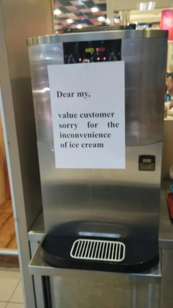 A taped note on a broken soft-serve dispenser showcases a charmingly broken translation fail reading "Dear my, value customer sorry for the inconvenience of ice cream."