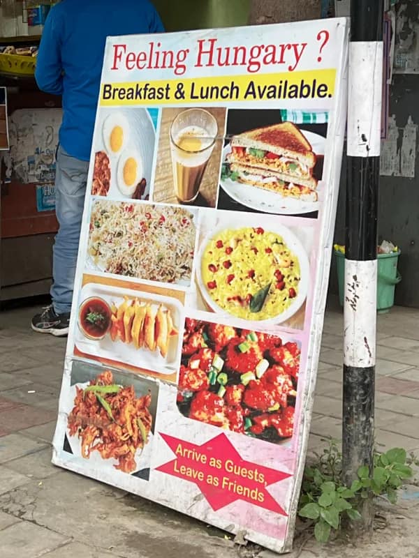 A sidewalk restaurant A-frame display board frames an amusing spelling-based translation fail by asking passersby if they are "Feeling Hungary?" next to pictures of breakfast dishes.