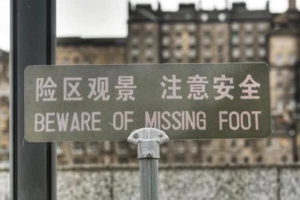A metal outdoor trail warning sign displaying Chinese characters delivers an alarming literal body-part translation fail reading, "BEWARE OF MISSING FOOT."