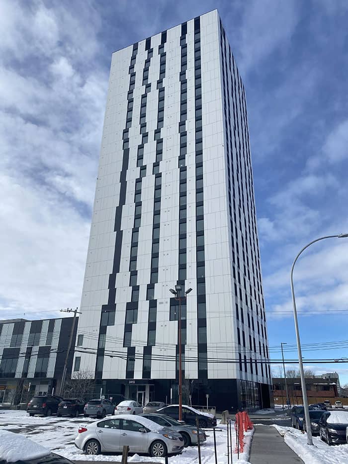 A tall white skyscraper with jagged, irregular vertical black lines running down the facade.