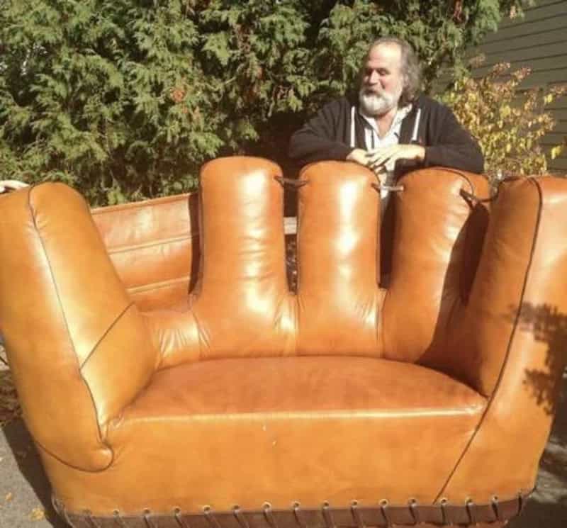 Large tan leather sofa shaped like a giant baseball catcher's mitt.